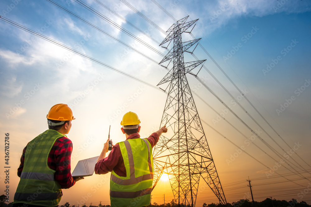 picture-of-two-electrical-engineers-checking-electrical-work-using-a-computer-standing-at-a-power-station-to-see-the-planning-work-at-high-voltage-electrodes-stockpack-adobe-stock Picture of two electrical engineers checking electrical work using a computer standing at a power station to see the planning work at high voltage electrodes.